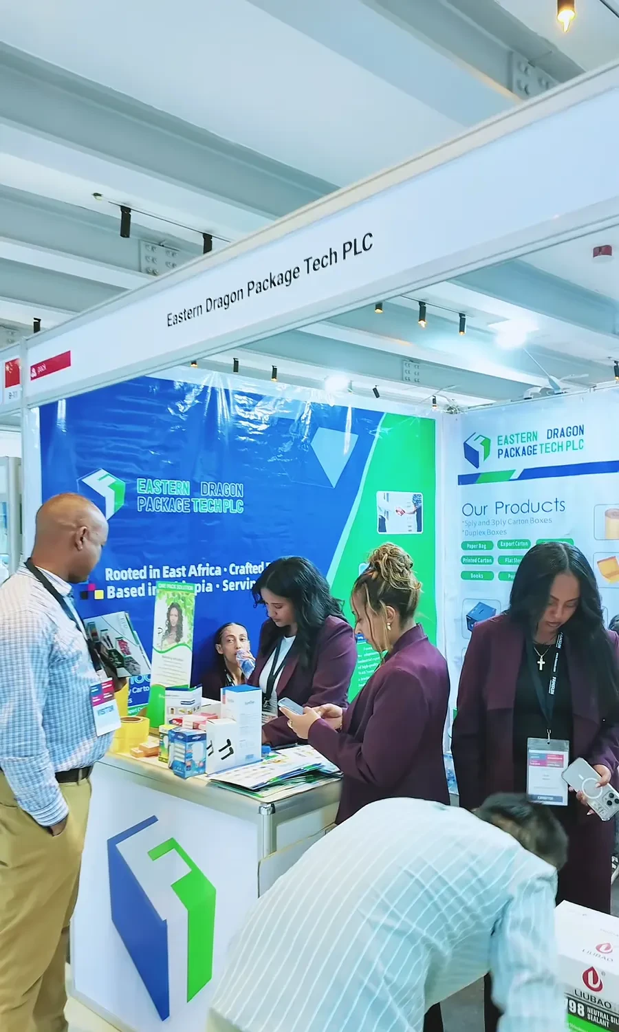 The Eastern Dragon exhibition team stands with visitors in front of the booth graphics.