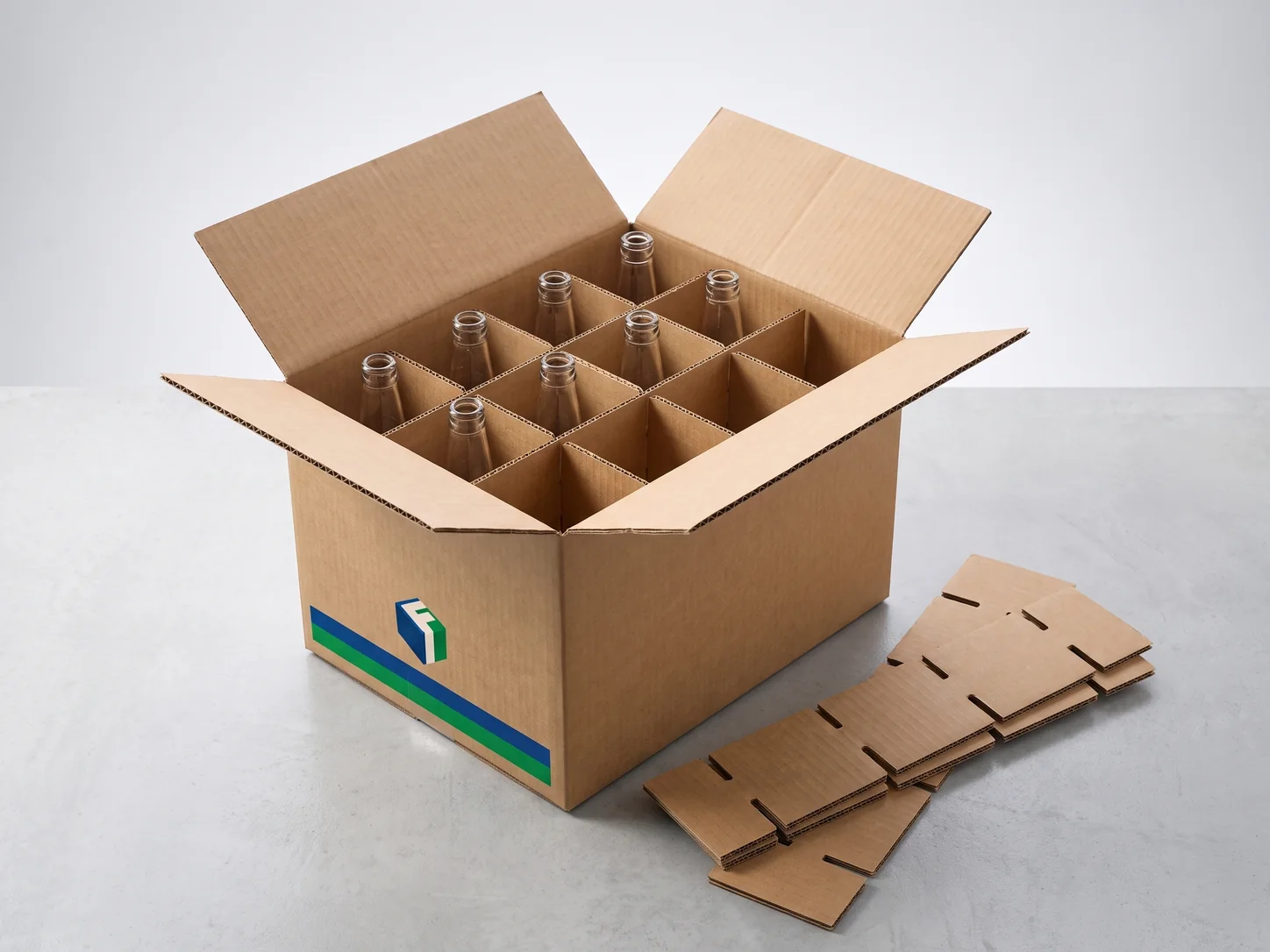 An open corrugated carton with an interlocking partition grid holding glass bottles, with loose partition strips beside it.