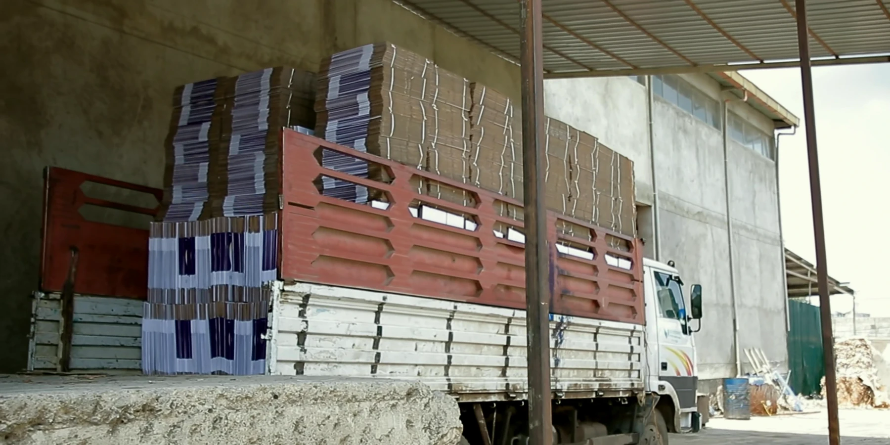 A truck is loaded with bundled finished cartons at the factory dispatch bay.