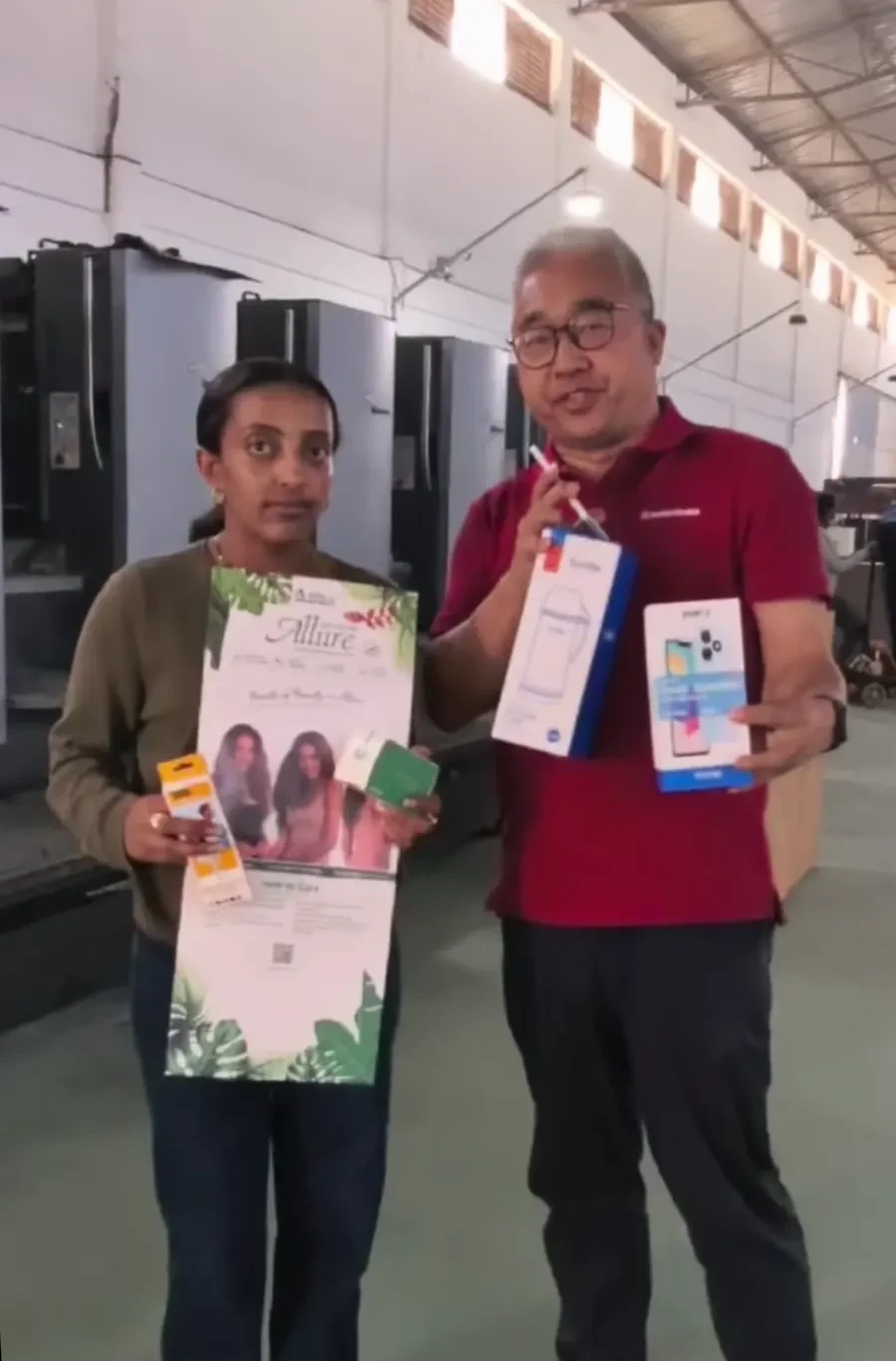 Two factory representatives hold examples of printed packaging products.