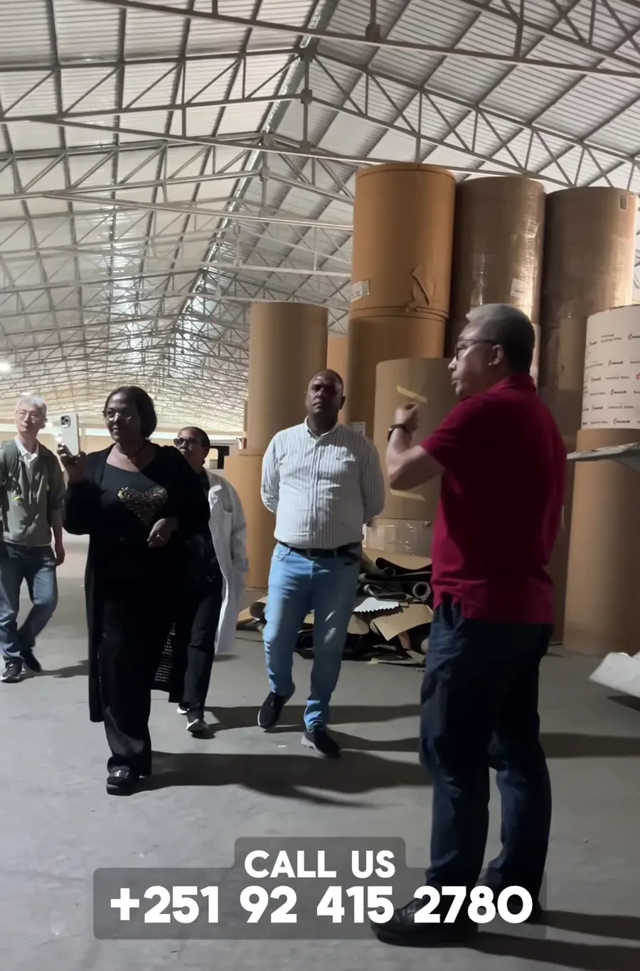 Visitors and Eastern Dragon staff walk through the paper-roll area of the factory.