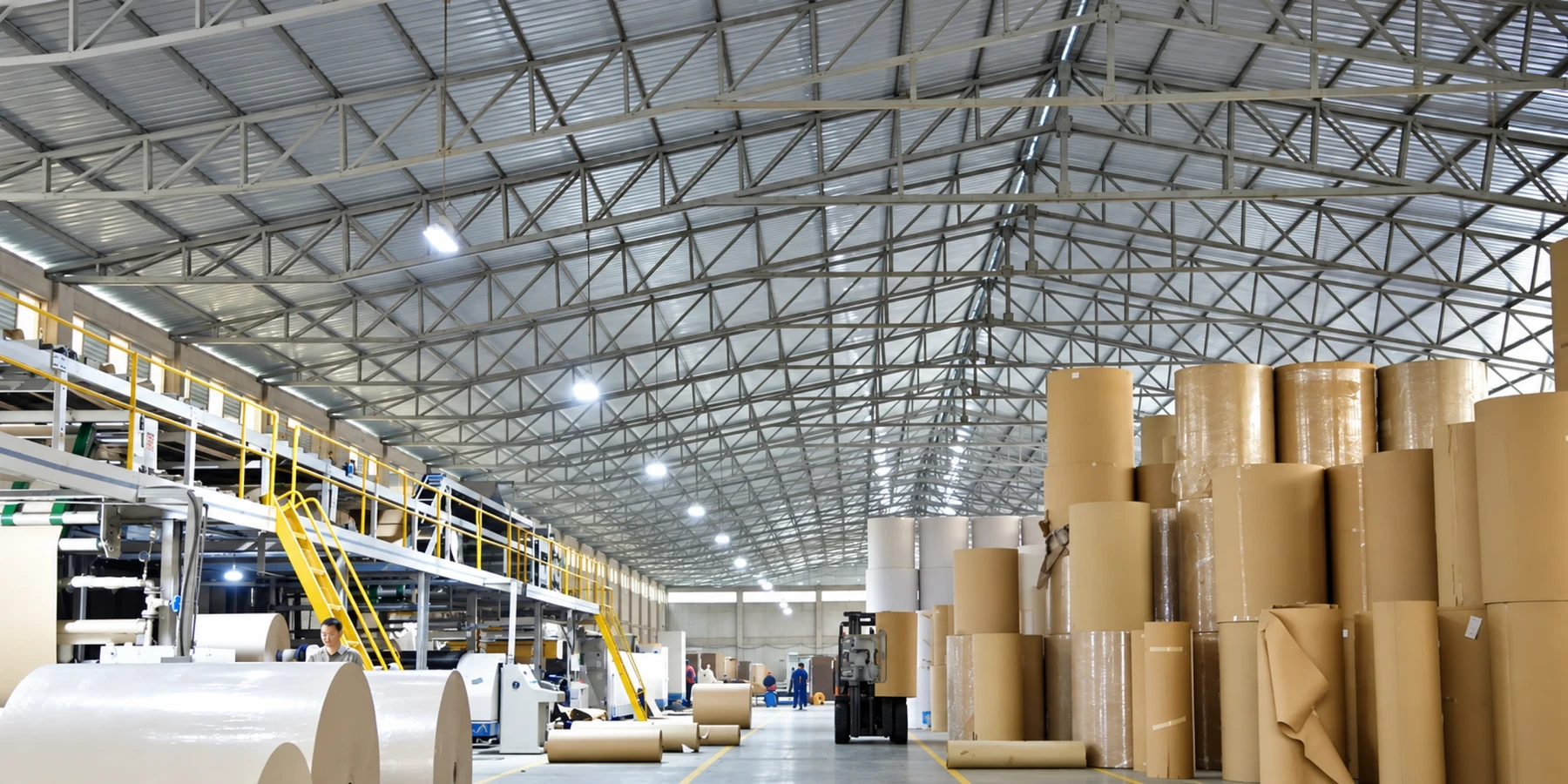 Wide interior view of the production hall with reels, machinery and stacked materials.