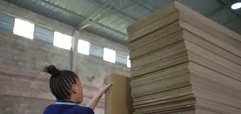 A factory team member checks a tall stack of corrugated board at Eastern Dragon.