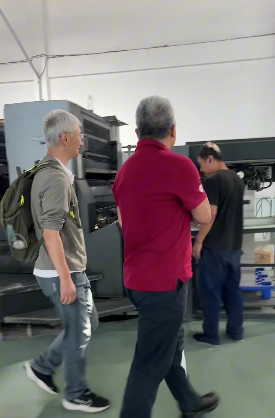 Factory visitors inspect a large printing machine with an Eastern Dragon guide.