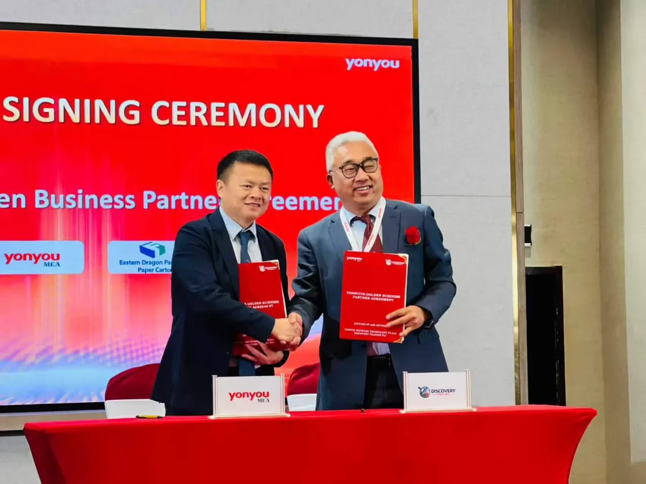 Representatives shake hands and hold signed Yonyou Golden Business Partner Agreement folders at the Addis Ababa ceremony.